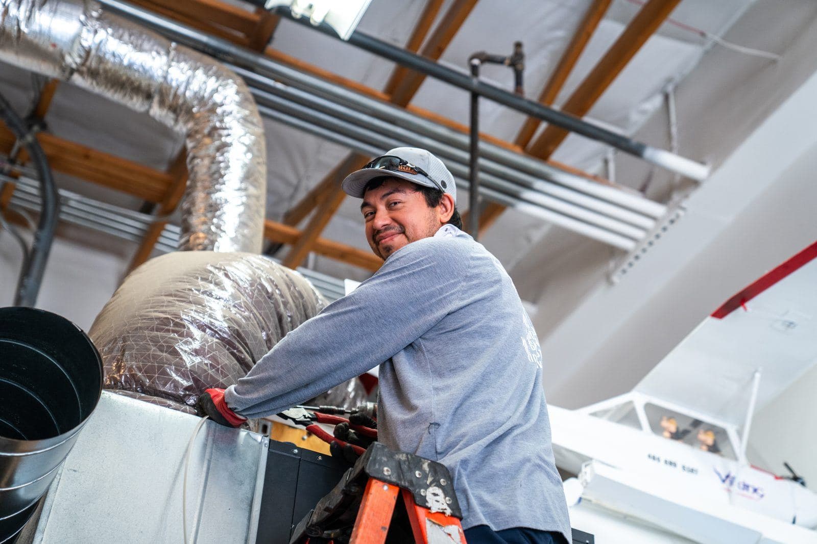 HVAC technician installing ductwork in an attic