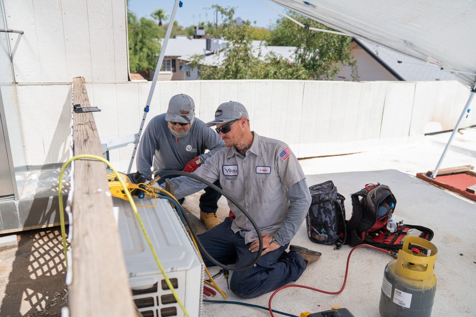 Two HVAC technicians servicing a rooftop unit