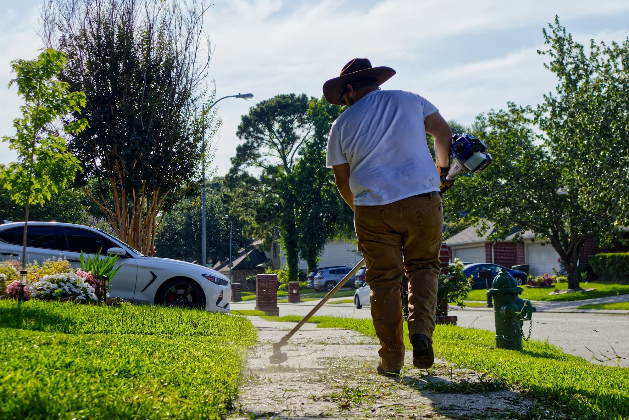 Landscaper trimming along a residential sidewalk
